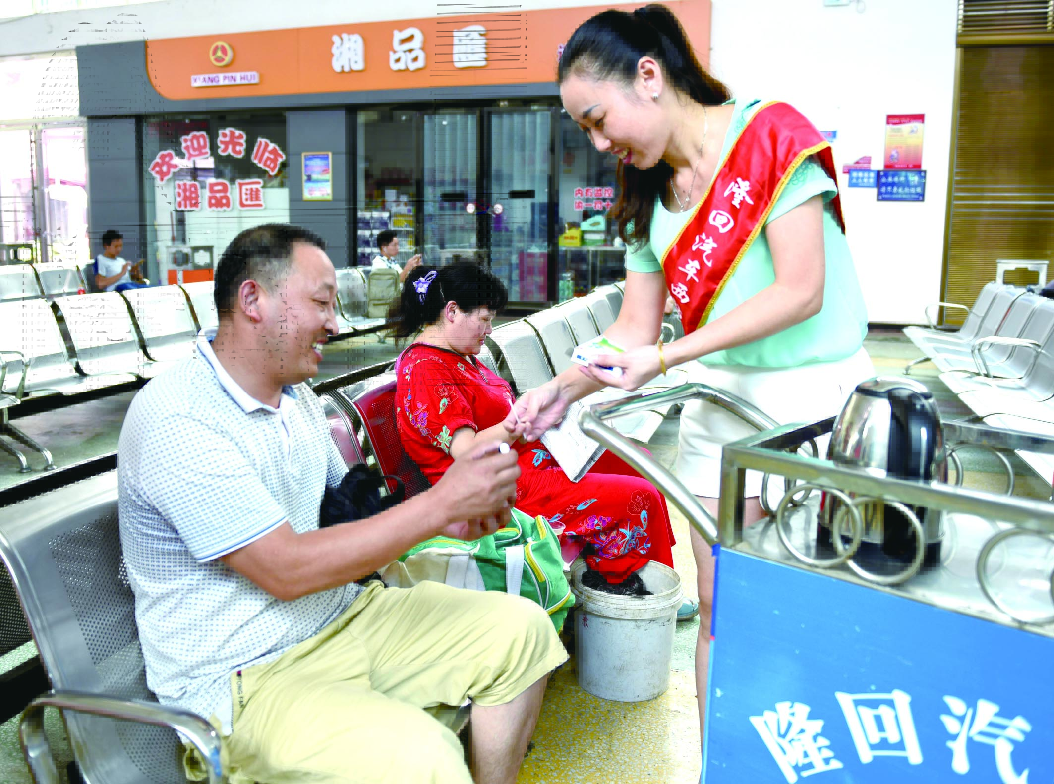 隆回分公司汽車西站工作人員正在為旅客免費贈送藿香正氣水。